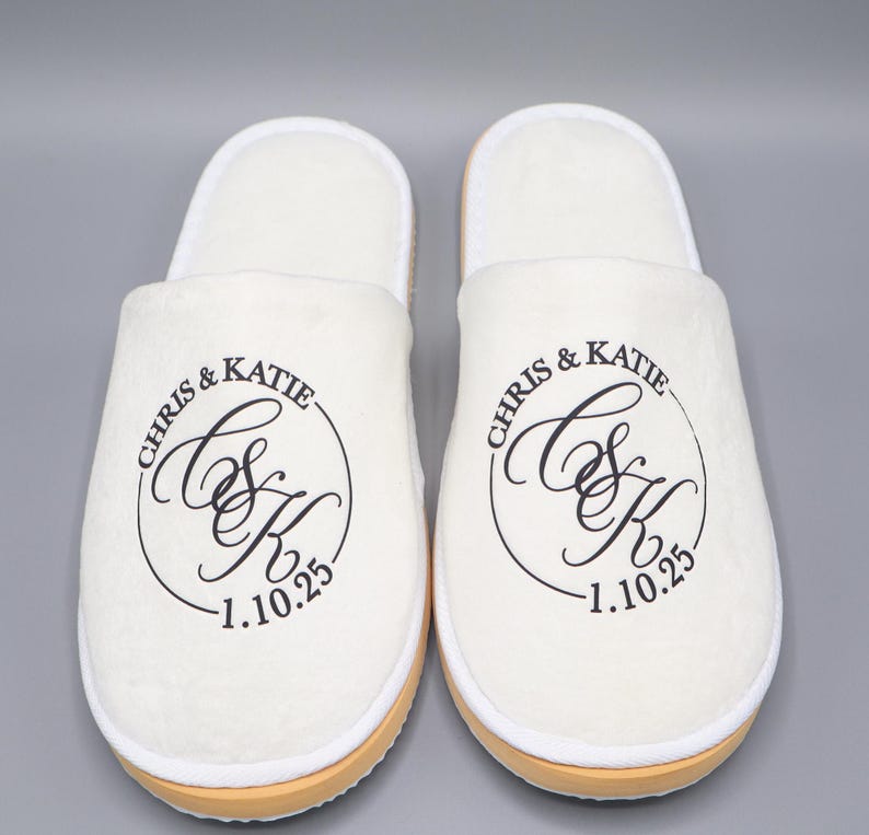 May include: A pair of white slippers with black embroidered text that reads "Chris & Katie C&K 1.10.25".