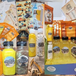 May include: A construction-themed kit with various bottles and bags filled with colorful sprinkles and candies. The bottles have labels with Spanish text. The kit includes stickers and instructions, all in a box.