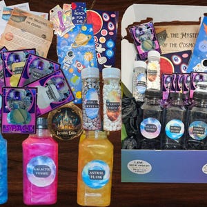 May include: A space-themed gift box with a variety of items, including colorful bottles, jars of sprinkles, and cards with space-themed illustrations. The box is decorated with a purple and white pattern and the text "Love your space" is printed on the front.