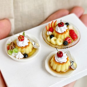 Può includere: Mini dessert su piatti bianchi. Ogni dessert presenta una base di crema pasticcera sormontata da panna montata e una ciliegia. Un piatto ha una varietà di frutta, tra cui fragole, mirtilli e fette di banana. Un piccolo cucchiaio è appoggiato accanto a ogni dessert.