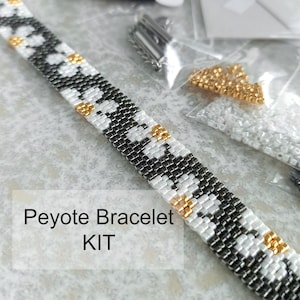 Può includere: Un kit per braccialetto Peyote con un design di perline nere, bianche e dorate. Il braccialetto è parzialmente costruito, con perline aggiuntive, filo e una chiusura visibili. Il testo "Peyote Bracelet KIT" è visualizzato.