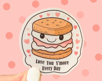 May include: A sticker with a cartoon s'more with a smiling face. The s'more is made of two graham crackers and a marshmallow. The sticker has pink hearts and the text "Love You S'more Every Day".