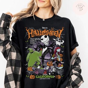 May include: Black t-shirt featuring a Halloween-themed graphic with Jack Skellington, Sally, and other characters. The design includes the text "This is Halloween" and "Everybody make a scene". The shirt also has the text "Disney California Adventure".