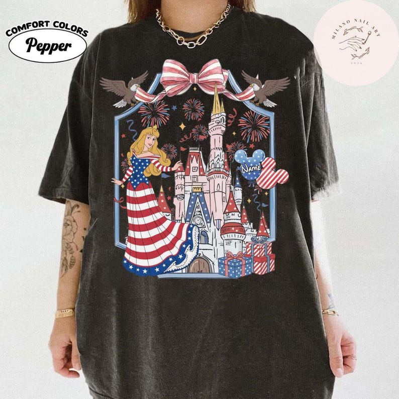 May include: Black Comfort Colors t-shirt with a patriotic design. The graphic includes a princess in a red, white, and blue dress, a castle, fireworks, and a Mickey Mouse head. The shirt also has the text "Name" and the brand name "Pepper".