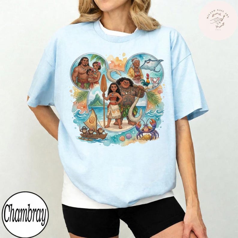 May include: A light blue t-shirt featuring a large graphic print of characters from the movie Moana arranged within a Mickey Mouse ear silhouette. The design includes Moana, Maui, Pua, Heihei, and other tropical elements like a boat and ocean.