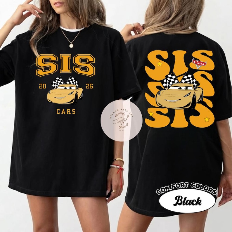 May include: Black t-shirt with a gold graphic featuring the word "SIS", the numbers "20" and "26", and a cartoon car with a checkered flag. The back of the shirt has a similar design. The shirt is labeled "Comfort Colors Black".