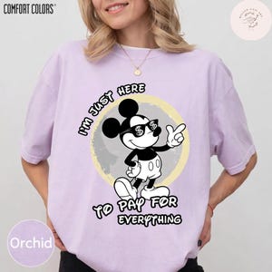 May include: Orchid-colored Comfort Colors t-shirt featuring a graphic of Mickey Mouse wearing sunglasses with dollar signs. The text reads "I'm just here to pay for everything."