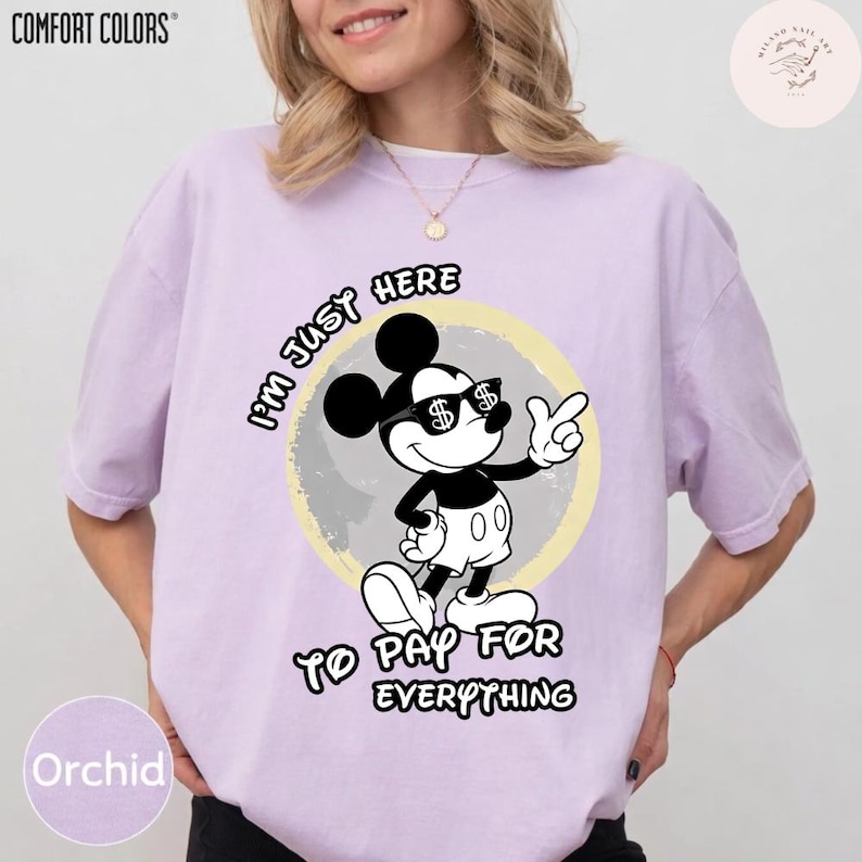 May include: Orchid-colored Comfort Colors t-shirt featuring a graphic of Mickey Mouse wearing sunglasses with dollar signs. The text reads "I'm just here to pay for everything."