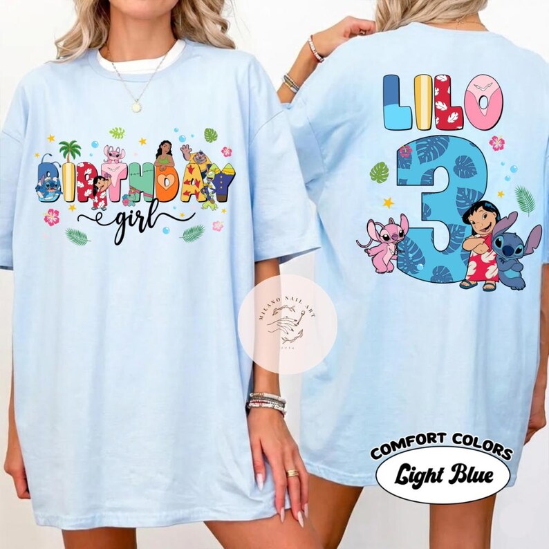 May include: Light blue t-shirt with the text "Birthday Girl" and various cartoon characters on the front. The back of the shirt features the word "Lilo", the number "3", and cartoon characters. The shirt is labeled "Comfort Colors Light Blue".