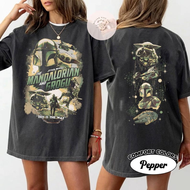 May include: Dark grey t-shirt featuring a Star Wars design with The Mandalorian and Grogu. The front graphic includes the text "This is the Way." The back of the shirt has additional Star Wars imagery. The shirt is labelled "Comfort Colors Pepper."