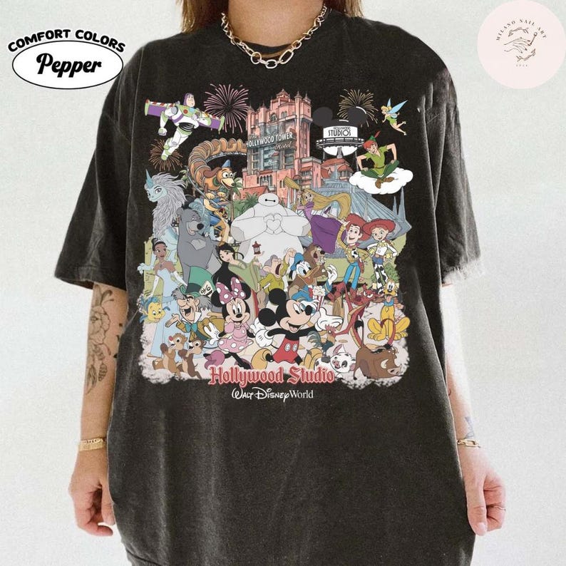 Puede incluir: Camiseta gris oscuro Comfort Colors con un gr&aacute;fico colorido de personajes de Disney, incluyendo Mickey Mouse y Buzz Lightyear. El dise&ntilde;o incluye el texto "Hollywood Studio Walt Disney World".