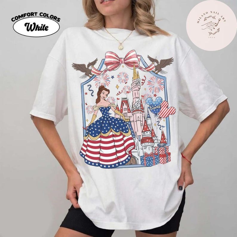May include: White Comfort Colors t-shirt with a patriotic graphic featuring a princess in a dress with stars and stripes, a castle, fireworks, and a bow. The shirt has the word "White" on it.