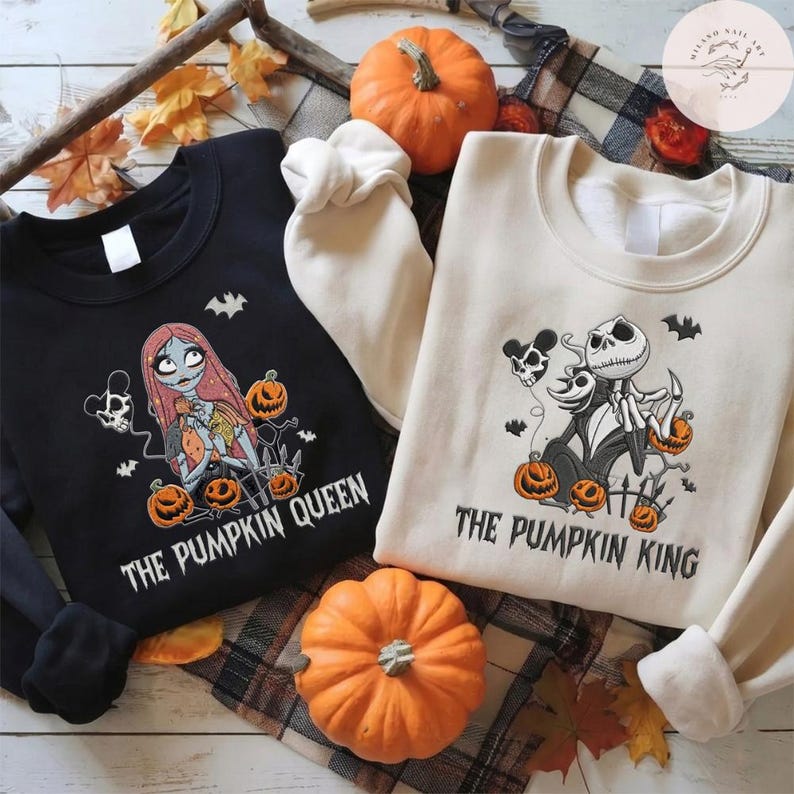 May include: A black sweatshirt featuring a graphic of a female character with long red hair and the text THE PUMPKIN QUEEN, and a cream sweatshirt featuring a graphic of a skeleton character and the text THE PUMPKIN KING, both with pumpkins.