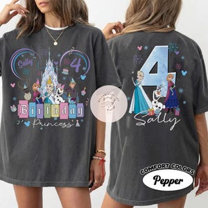 K&ouml;nnte beinhalten: Ein anthrazitfarbenes T-Shirt mit einem Grafikdruck von Figuren aus Die Eisk&ouml;nigin. Die Vorderseite zeigt den Text Birthday Princess mit dem Namen Sally und der Zahl 4. Die R&uuml;ckseite zeigt eine gro&szlig;e 4 mit Illustrationen von Elsa, Anna und Olaf.