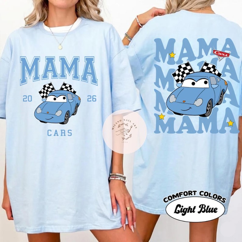 May include: Light blue t-shirt with the word "MAMA" in blue block letters and a cartoon car graphic. The front of the shirt has the text "20 26 CARS". The back of the shirt has the word "MAMA" repeated with a car graphic and the text "Comfort Colors Light Blue".