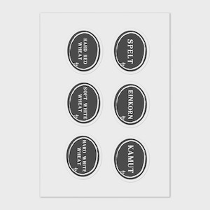 May include: Six oval stickers with black borders and white text, featuring wheat varieties: Hard Red Wheat, Spelt, Soft White Wheat, Einkorn, Hard White Wheat, and Kamut. Each sticker includes a small leaf design. The stickers are on a white background.
