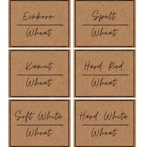 May include: Six brown rectangular labels with black borders and handwritten text. The labels read: "Einkorn Wheat", "Spelt Wheat", "Kamut Wheat", "Hard Red Wheat", "Soft White Wheat", and "Hard White Wheat".