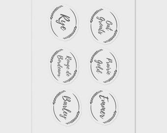 May include: Six circular stickers with handwritten text and wheat-like border designs. The stickers include the words "Rye", "Oat Groats", "Rouge de Bordeaux", "Prairie Gold", "Barley", and "Emmer". The stickers are arranged in two rows of three.