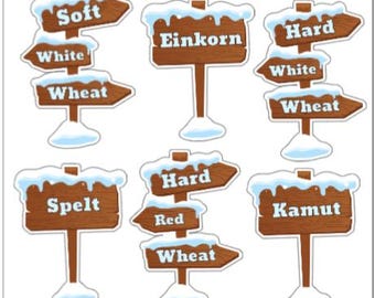 May include: A collection of wooden signposts with snow-covered tops. The signs display text such as "Soft", "White", "Wheat", "Einkorn", "Hard", "Spelt", "Red", and "Kamut". The signs are brown with white text and blue snow.