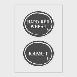 May include: Two dark grey oval stickers on a white background. The top sticker reads "HARD RED WHEAT" in white text. The bottom sticker reads "KAMUT" in white text. Both stickers have a white border and a small wheat graphic.