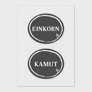 May include: Two dark grey circular stickers with white text. The top sticker reads "EINKORN" and the bottom sticker reads "KAMUT". Each sticker has a white, textured border and a small wheat sprig graphic.