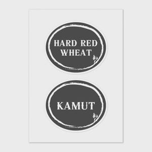 May include: Two dark grey circular stickers with white text. The top sticker reads "HARD RED WHEAT" and the bottom sticker reads "KAMUT". Both stickers have a white border and a small wheat graphic.