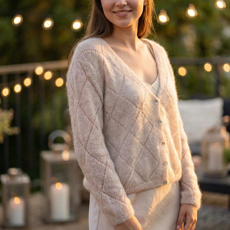 May include: A light beige cardigan with a diamond pattern and button closure. The V-neck sweater is made of a soft, textured knit fabric. The cardigan is a neutral color and has a relaxed fit.