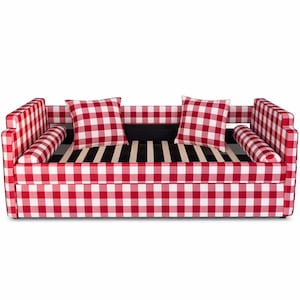May include: A red and white gingham patterned sofa with two square pillows and two bolster pillows. The sofa has a black and white striped base and a wooden frame. The sofa is a stylish piece of furniture.