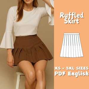 May include: A brown pleated skirt with the text "Ruffled Skirt" and a diagram of the skirt. The skirt is paired with a white long-sleeve top. The text "XS - 5XL SIZES PDF English" is also visible.