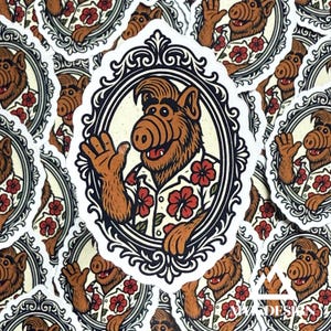 May include: A sticker featuring the character Alf in a Hawaiian shirt with red flower accents. The sticker has a white border with a decorative black and white frame. The background is filled with similar stickers.