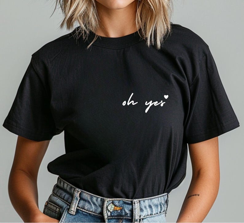 Puede incluir: Camiseta negra con texto blanco que dice "oh yes" con un peque&ntilde;o s&iacute;mbolo de coraz&oacute;n.