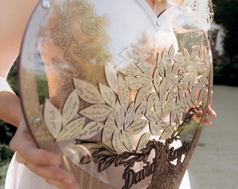 Peut inclure: Un livre d'or en bois en forme de cœur avec un motif d'arbre et les noms "David & Kayla" gravés en bas. L'arbre est décoré de petites feuilles en bois, chacune avec un message manuscrit.