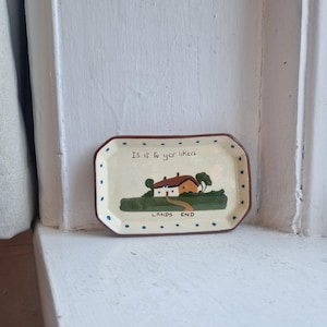 May include: A rectangular, cream-coloured tray with a brown border and blue polka dots. The tray features a painted landscape scene of a house with a red roof and the text "Is it fu yer liken?" and "LANDS END".