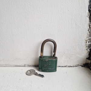 May include: A green metal padlock with a brass-coloured shackle, featuring the embossed text UNION, 5270, and MADE IN ENGLAND on the front. A matching silver-coloured metal key with the word UNION stamped on its head lies next to the padlock.