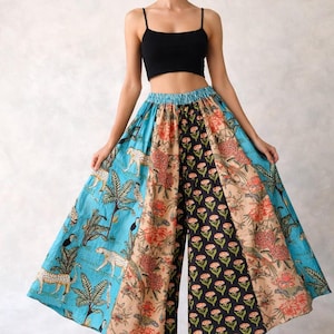 Può includere: Pantaloni palazzo a gamba larga con design patchwork e top corto nero. I pantaloni presentano pannelli blu con ghepardi, beige con motivi floreali e neri con stampe floreali. La modella indossa sandali color beige.