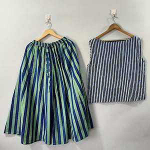 May include: A two-piece outfit comprising a skirt and a sleeveless top. The skirt is full length, with vertical blue and green stripes. The top is sleeveless with vertical blue and white stripes. Both items are suspended on wooden hangers.