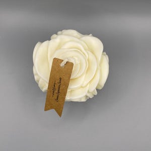 Pu&ograve; includere: Una candela bianca a forma di rosa con un'etichetta marrone che recita "Sweet Signature Scents - Madison".