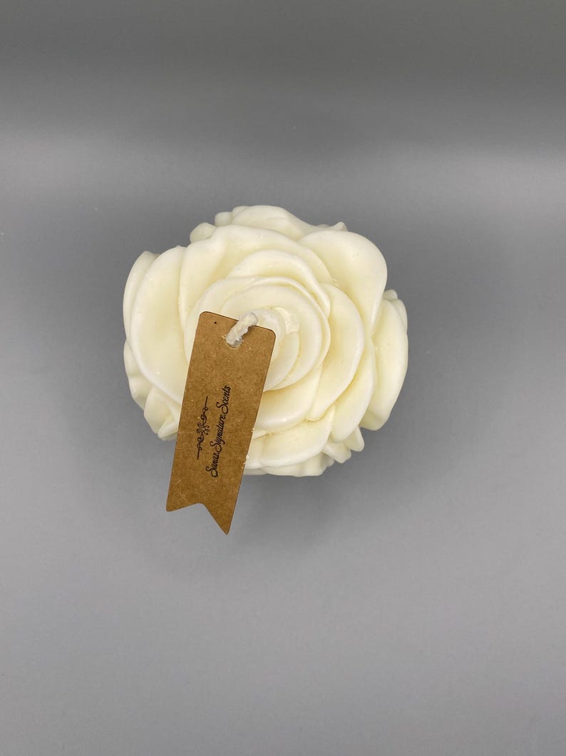 Pu&ograve; includere: Una candela bianca a forma di rosa con un'etichetta marrone che recita "Sweet Signature Scents - Madison".