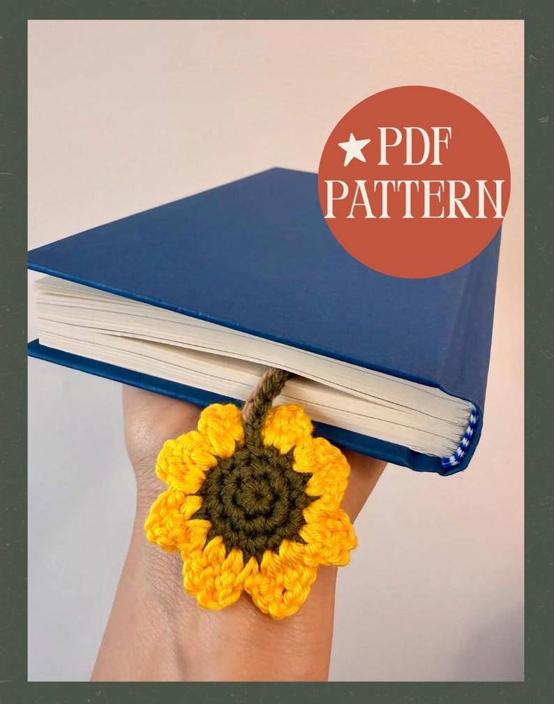 May include: A blue hardcover book with a handmade crochet sunflower bookmark. The bookmark features a yellow sunflower with a green center and a brown stem. The text "PDF PATTERN" is in a red circle.