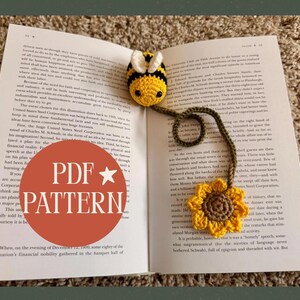 May include: A handmade crochet bookmark featuring a yellow and black bee with a sunflower at the end. The bookmark is attached to a book. The image also contains the text "PDF PATTERN" in a red circle.