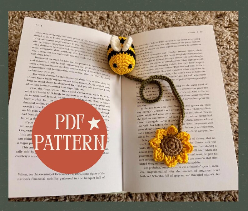 May include: A handmade crochet bookmark featuring a yellow and black bee with a sunflower at the end. The bookmark is attached to a book. The image also contains the text "PDF PATTERN" in a red circle.