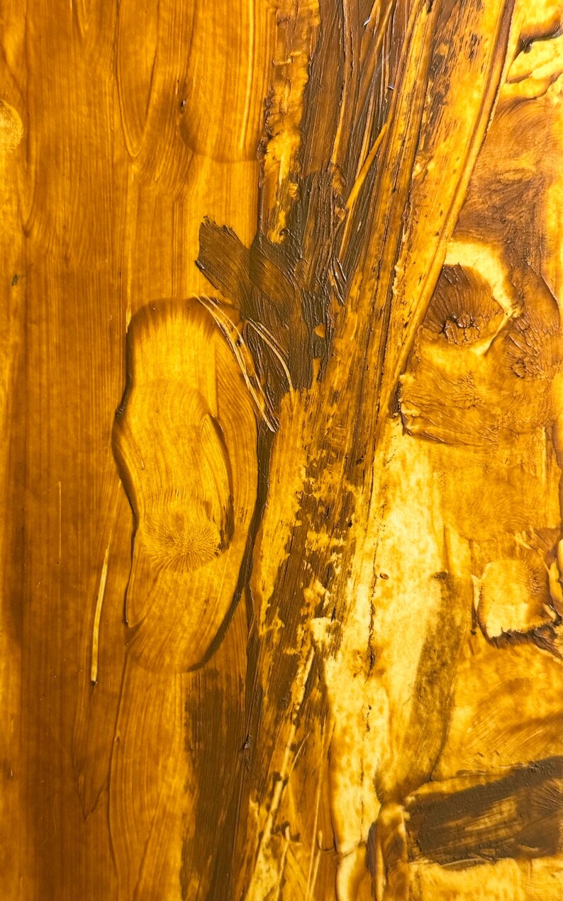 May include: Abstract artwork with a textured surface. The painting features a blend of golden yellow and brown hues, with visible brushstrokes and a layered effect. The artwork has a warm, earthy tone.