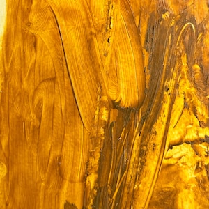 May include: Abstract artwork with a textured surface. The image features a blend of golden yellow and brown hues, applied with visible brushstrokes. The strokes create a dynamic, swirling pattern across the canvas, suggesting movement and depth.