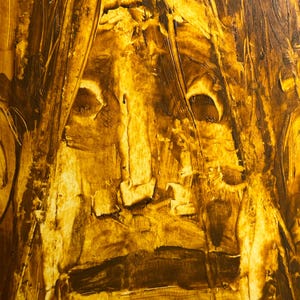 May include: Abstract painting with a textured surface, featuring a face-like composition in shades of brown and yellow. The artwork uses thick brushstrokes to create a sense of depth and movement, with the central focus resembling a human face.