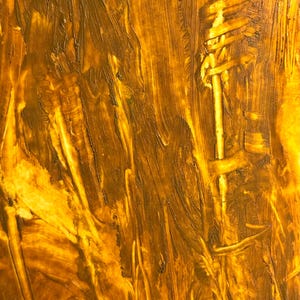 May include: Abstract artwork with a textured surface. The painting features a blend of golden yellow and brown hues, applied with visible brushstrokes. The composition has a vertical orientation, with a central, lighter-toned element.