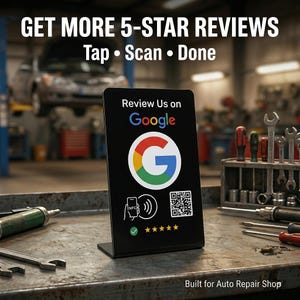May include: A black display stand with the Google logo and the text "Review Us on Google." The stand also features a QR code, NFC symbol, and five stars. The text "GET MORE 5-STAR REVIEWS" is at the top. The background is a mechanic's workshop.