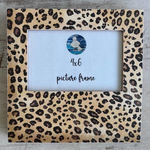 May include: A square picture frame with a leopard print pattern in shades of tan, brown, and black. The frame is designed for a 4x6 inch photo and features the text "4x6 picture frame".