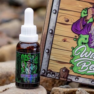 May include: A 1 oz bottle of beard oil with a green, black, and white label. The label features a cartoon wizard with a beard and a pointed hat. The text on the label reads "Rosemary & Mint".