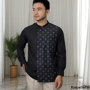 Può includere: Camicia nera a maniche lunghe con colletto alla coreana. Il lato destro della camicia presenta un motivo geometrico nei toni del grigio e del nero. Un capo d'abbigliamento elegante.