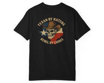 Peut inclure: T-shirt noir avec un motif de crâne portant un chapeau de cowboy, sur fond de drapeau texan. Le texte indique "Texan by Nature, Rebel by Choice" en cercle autour du crâne.